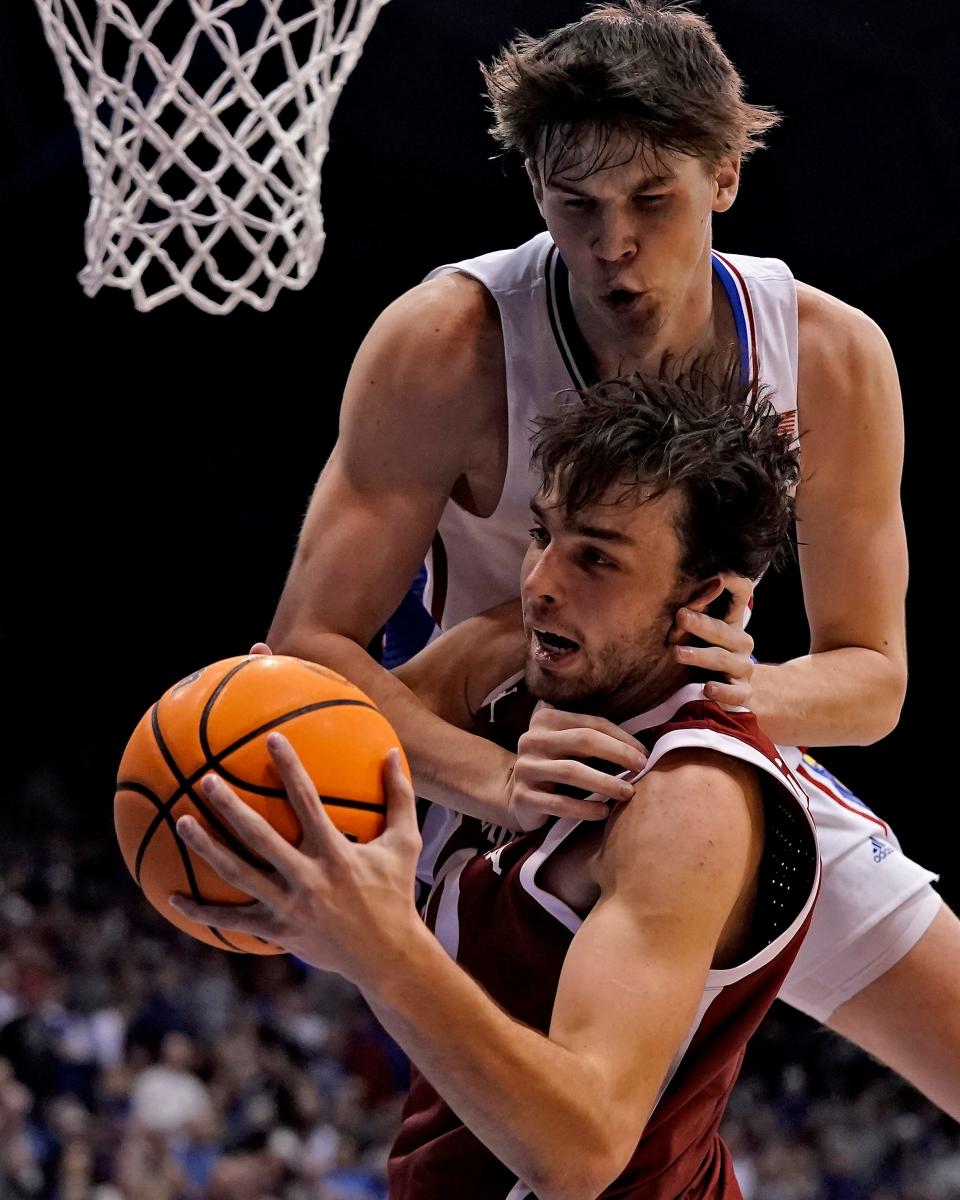 Kansas forward Zach Clemence, top, and Oklahoma forward Sam Godwin (10) chase a loose ball during the second half of an NCAA college basketball game Tuesday, Jan. 10, 2023, in Lawrence, Kan. Kansas won 79-75. (AP Photo/Charlie Riedel)