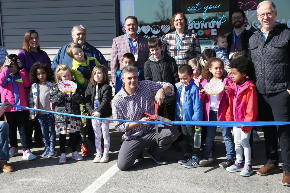 The Newmarket Business Association organized a ribbon cutting for Donut Love in its third location in Newmarket Feb. 27, 2024. Operation Manager James Keegan gets ready to cut the ribbon as owner Eric Goodwin and children from Newmarket Recreation take part.
