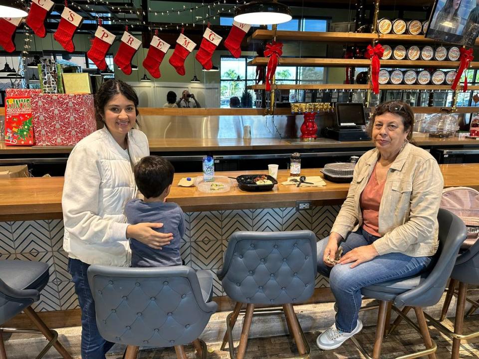 Andrea García, su hijo y su madre Teresa García tomando un descanso mientras cenan en la cafetería de Whole Foods el 7 de diciembre de 2023. La familia hacía sus compras en la tienda de Pinecrest y, para mayor comodidad, llevó comida de las barras de ensaladas frías y calientes para almorzar y hacer sus compras en un solo viaje a la tienda.