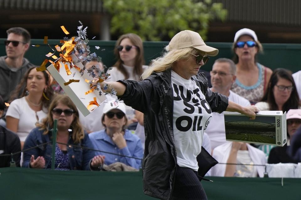 FILE - A Just Stop Oil protester runs onto Court 18 and releases confetti and a jigsaw puzzle pieces on day three of the Wimbledon tennis championships in London, July 5, 2023. Climate activists have spraypainted a superyacht, blocked private jets from taking off and plugged holes in golf courses this summer as part of an intensifying campaign against the emissions-spewing lifestyles of the ultrawealthy. (AP Photo/Alastair Grant, File)