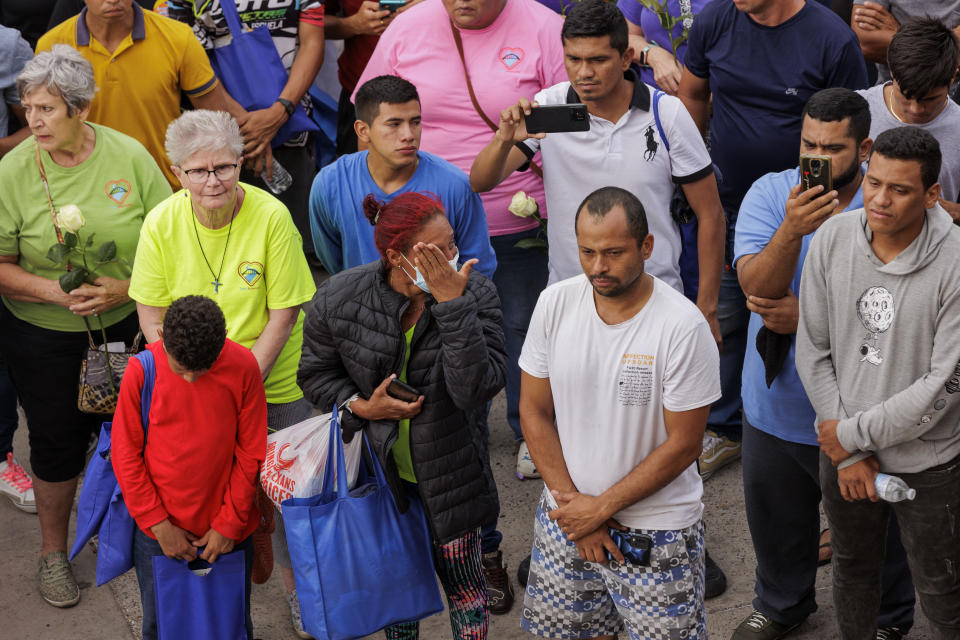 Migrants and community members listen to and record speakers during a vigil for the eight migrants that were killed and several others that were injured the day before while waiting at a bus stop, in Brownsville, Texas, Monday, May 8, 2023. (AP Photo/Michael Gonzalez)