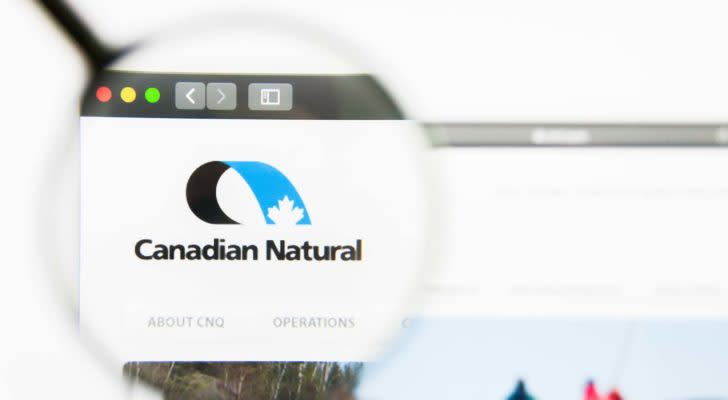 A magnifying glass zooms in on the website for Canadian Natural Resources (CNQ).