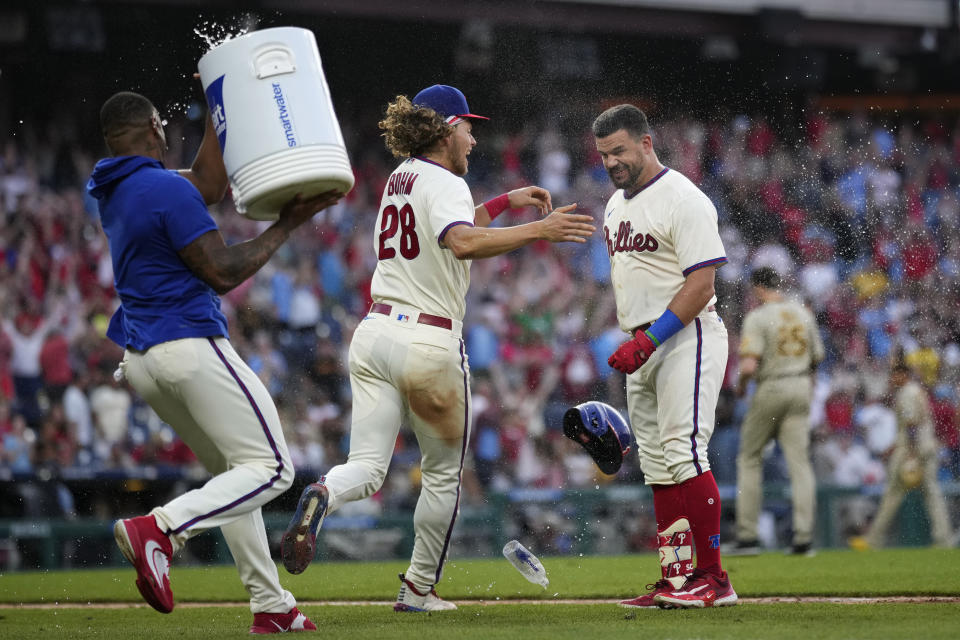 Philadelphia Phillies' Kyle Schwarber, right, celebrates with Alec Bohm, center, and Gregory Soto after hitting a game-winning RBI-sacrifice fly against San Diego Padres relief pitcher Tim Hill during the 12th inning of a baseball game, Sunday, July 16, 2023, in Philadelphia. (AP Photo/Matt Slocum)