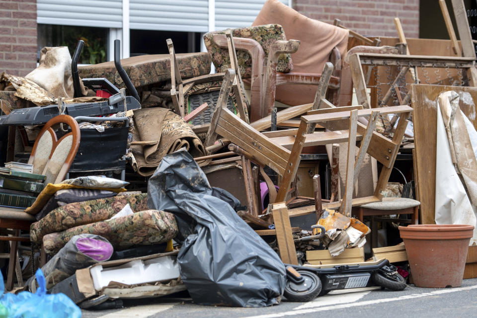 A pile of discarded furniture stands in front of a house in the district of Blessem, in Ergfstadt, Germany, Thursday July 22, 2021. In the flood disaster area of Erftstadt-Blessem, some residents are being allowed back into their homes to clear debris after heavy rains caused devastating floods. (Marius Becker/dpa via AP)