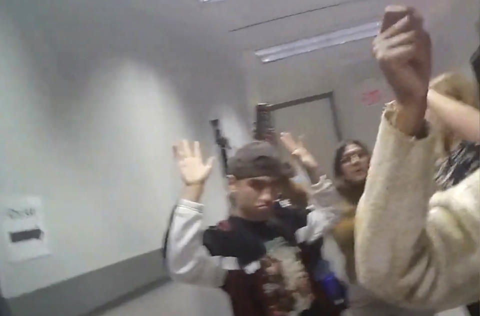 In this image made from body camera footage provided by the Las Vegas Metro Police Department, civilians leave a building on the University of Nevada, Las Vegas campus with their hands up, Wednesday, Dec. 6, 2023, in response to reports of a shooting. Police body camera footage from the shooting, which left three people dead and one wounded, was released Wednesday, Dec. 20. (Las Vegas Metro Police Department via AP)