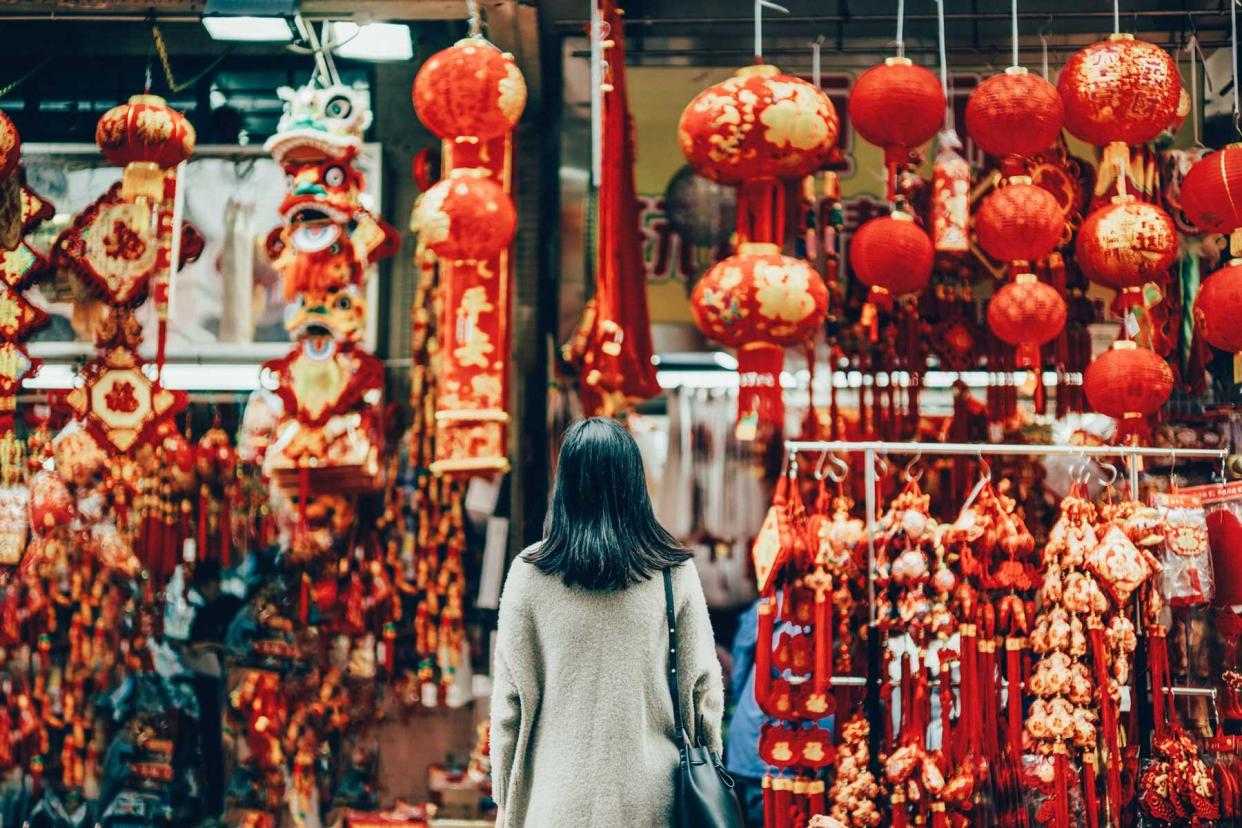 Rear view of woman standing against various Lunar New Year decorations and ornaments on city street