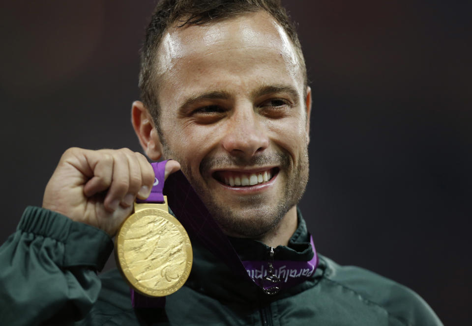 FILE - In this Saturday, Sept. 8, 2012, file photo, Gold medalist South Africa's Oscar Pistorius poses with his medal during the ceremony after winning the men's 400 meters T44 category final during the athletics competition at the 2012 Paralympics, in London. With his athletic triumphs tarnished by the killing of his girlfriend, Reeva Steenkamp. Pistorius, now 27, faces possibly being sent to prison until he is older than 50. Pistorius goes on trial Monday March 3, 2014. (AP Photo/Matt Dunham, File)
