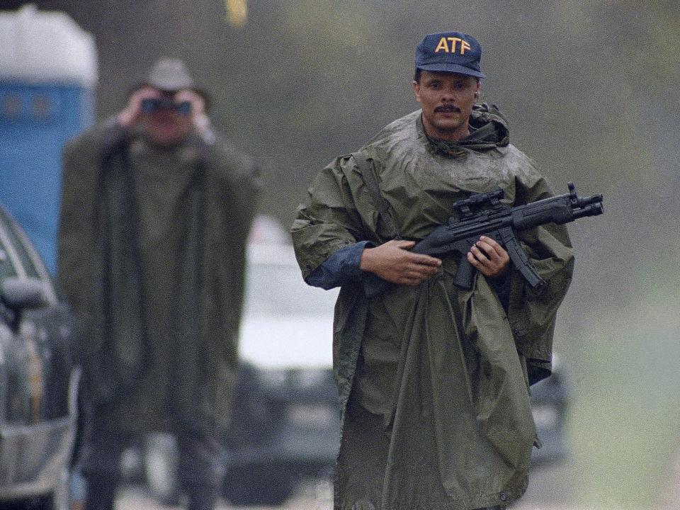 An Alcohol, Tobacco and Firearms agent wearing a hat that says ATF stands in the rain at a barricade north of the Branch Davidian compound near Waco, Texas on Monday, March 22, 1993.