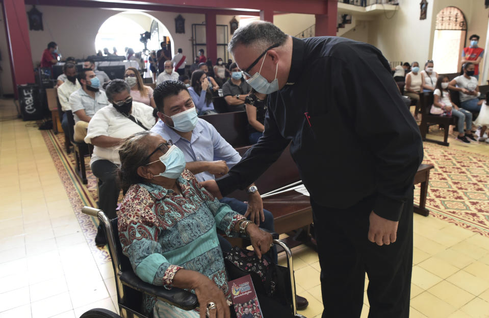 Sergio Valverde Espinoza, right, a Catholic priest of the Cristo Rey church who modified a popular song called "Sopa de Caracol," or Snail Soup in English, greets the faithful during a Mass in San Jose, Costa Rica, Sunday, May 2, 2021. Valverde changed the song's lyrics to a message calling for the use of face masks and care during the pandemic. (AP Photo/Carlos Gonzalez)