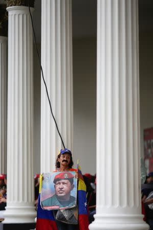 A woman holds a picture of Venezuela's late President Hugo Chavez at the courtyard on the grounds of the building housing the National Constituent Assembly during the swearing in ceremony for newly elected governors, in Caracas, Venezuela October 18, 2017. REUTERS/Marco Bello