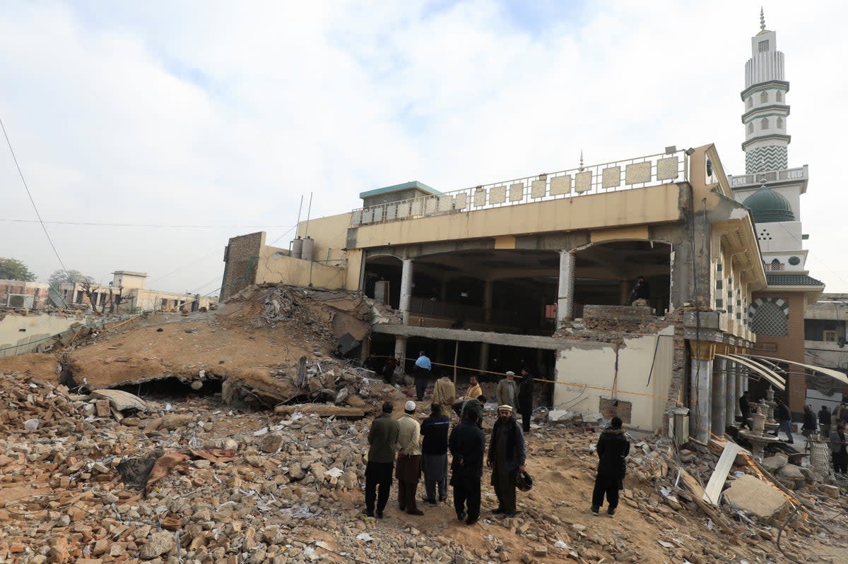 People stand amid the rubble, following a suicide blast in a mosque in Peshawar (REUTERS)