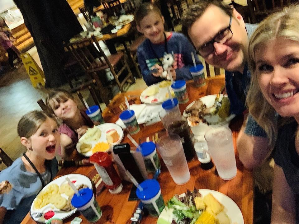 A family sitting at a table eating a meal and taking a selfie.