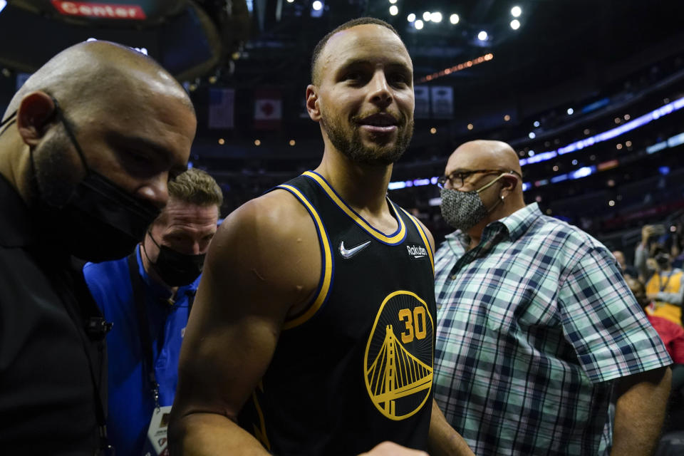 Golden State Warriors guard Stephen Curry, center, leaves the court after winning an NBA basketball game against the Los Angeles Clippers 105-90 in Los Angeles, Sunday, Nov. 28, 2021. (AP Photo/Ashley Landis)