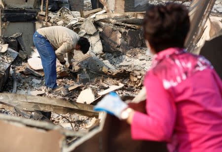 Alex Ham, left, and his mother Lilly Ham search for a safe in Lilly's home that was destroyed in wildfire that tore through Santa Rosa, California, U.S., October 15, 2017. REUTERS/Jim Urquhart