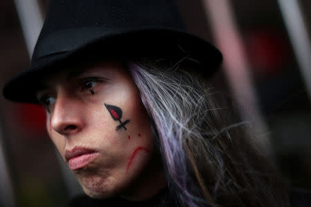 A woman shows her cheek with a sad face painted on it during a demonstration to demand policies to prevent gender-related violence in Buenos Aires, Argentina, October 19, 2016. REUTERS/Marcos Brindicci
