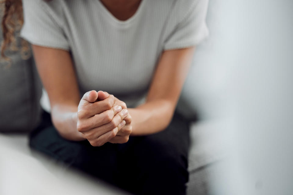 A woman sitting holding her hands.