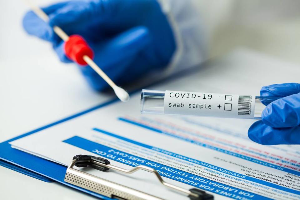 A medical worker holds a coronavirus COVID-19 NP OP swab sample test kit and nasal collection equipment.