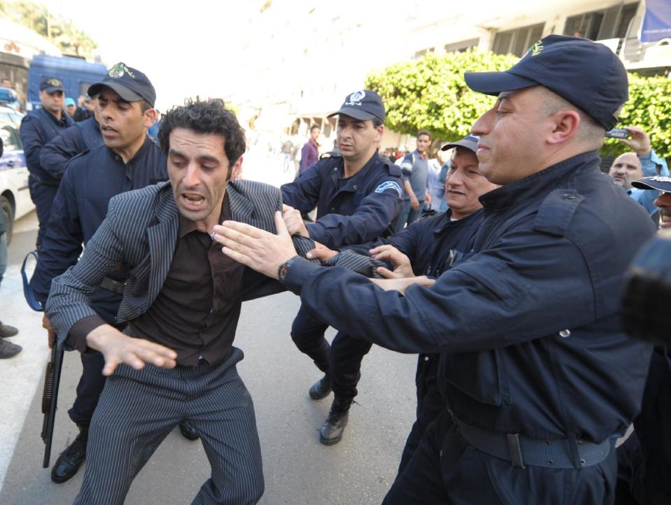 Algerian police officers detain an activist protesting against the president Abdelaziz Bouteflika running for a fourth term in Thursday's elections in Algiers, Wednesday, April 16, 2014. President since 1999, Abdelaziz Bouteflika,77, is running for a 4th term despite being hit by a stroke last year that left him speaking and moving with difficulty. Six candidates are running for the powerful presidency in the April 17 elections. (AP Photo/Sidali Djarboub)