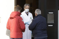 A pharmacist delivers medicine to customers outside his pharmacy in Codogno, near Lodi, Northern Italy, Saturday, Feb. 22, 2020. A dozen towns in northern Italy are on effective lockdown after the new virus linked to China claimed a first fatality in Italy and sickened an increasing number of people. The secondary contagions have prompted local authorities in towns of Lombardy and Veneto to order schools, businesses, and restaurants closed, and to cancel sporting events and Masses. (AP Photo/Luca Bruno)