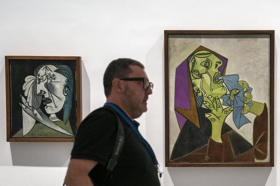 A man walks past two paintings by Pablo Picasso after a news conference to present the "Picasso Year" events, marking the 50th anniversary of the painter's death, at the Reina Sofia Museum in Madrid, Spain, Monday, Sept. 12, 2022. Against the backdrop of Picasso's iconic anti-war painting, "Guernica," the culture ministers of France and Spain have gathered in Madrid to kick off a year of commemorative acts to celebrate the 50th anniversary of the death of the Spanish artist who revolutionized the world of art. (AP Photo/Andrea Comas)