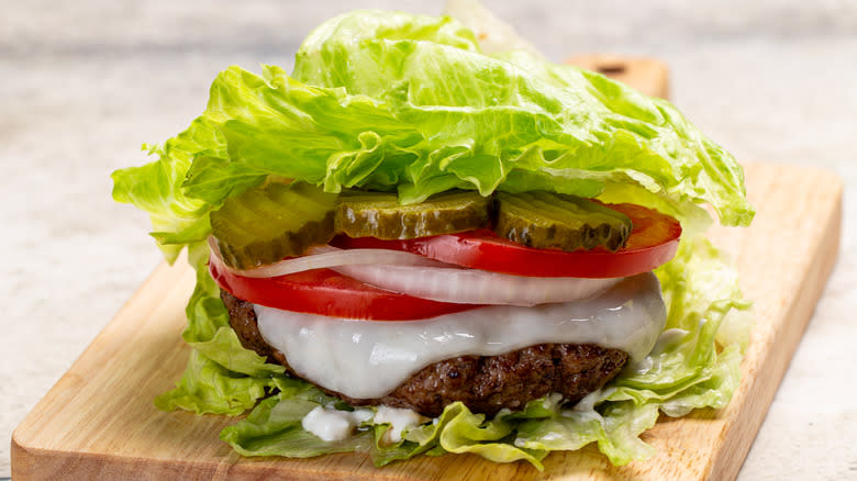 Lettuce-wrapped cheeseburger on cutting board