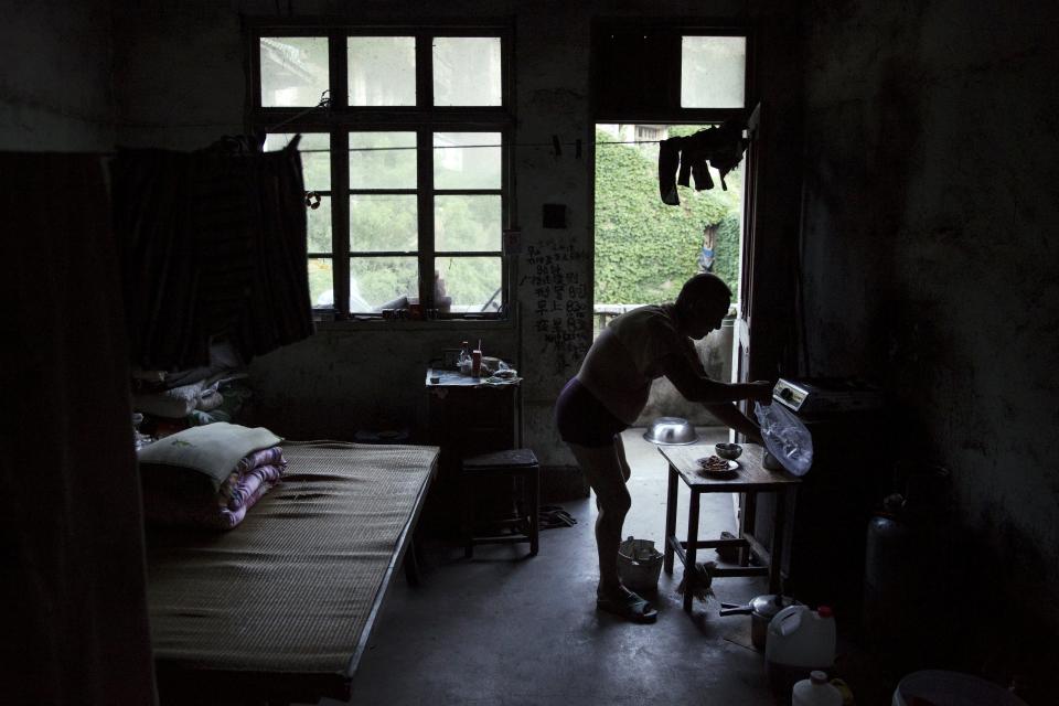 Sun Ayue, one of very few residents of the abandoned fishing village of Houtouwan on the island of Shengshan prepares dinner at the room where he lives July 25, 2015. (REUTERS/Damir Sagolj)