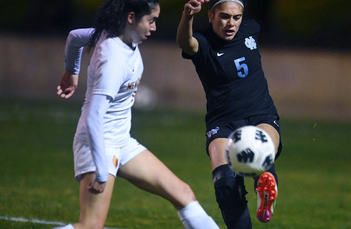 Clovis North’s Rebhia Mansour, right, kicks the ball away with Menlo-Atherton’s Fabiana Bolanos to the left in CIF Northern California Regional girls playoff game action Tuesday, Feb. 2, 2023 in Clovis.