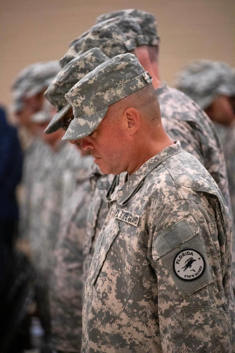 Miembros de la Guardia Estatal de la Florida inclinan sus cabezas en oración durante la ceremonia de graduación de la Guardia Estatal de la Florida en el Centro de Entrenamiento Conjunto de Camp Blanding en Starke, Florida, el 30 de junio de 2023.