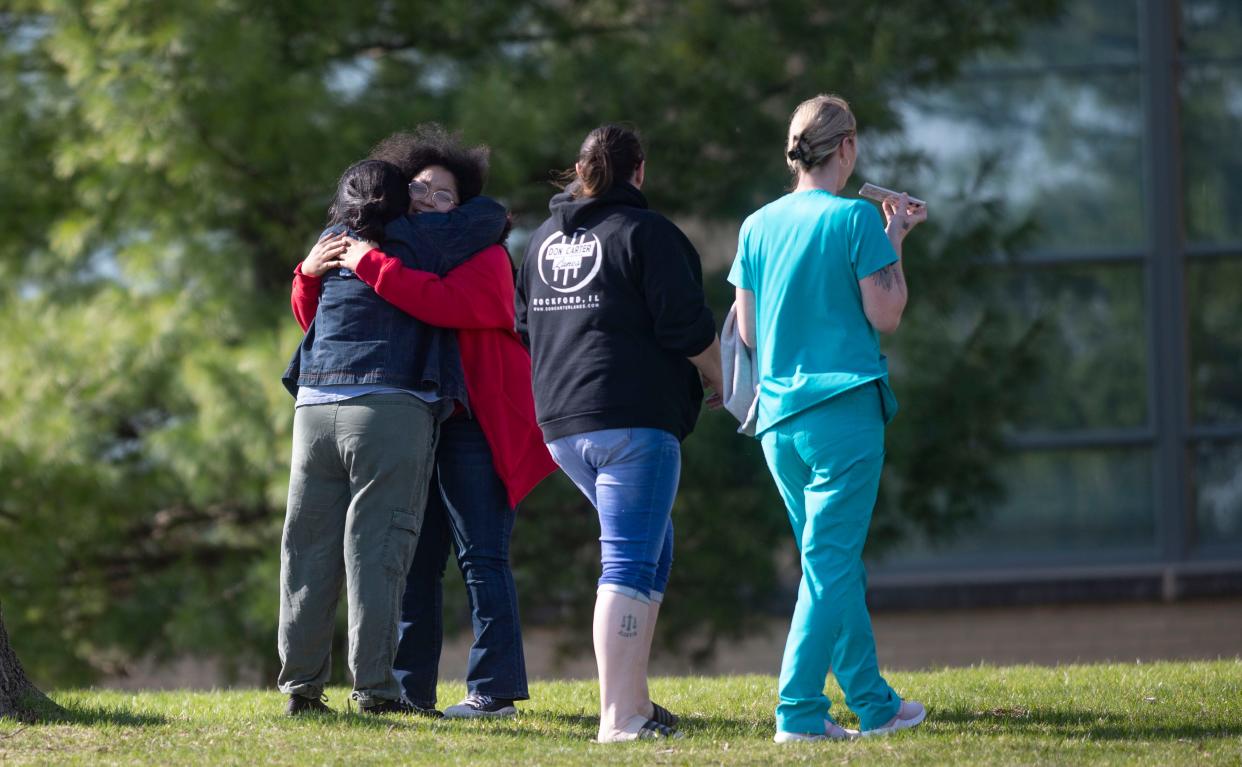 People comfort each other on the lawn outside East High School on Wednesday, April 12, 2023, after a report of a shooting at the school in Rockford. The report was false, part of a nationwide prank.