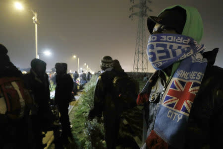 Migrants with their belongings line up as their evacuation and transfer to reception centers in France, and the dismantlement of the camp called the "Jungle" in Calais, France starts. REUTERS/Philippe Wojazer