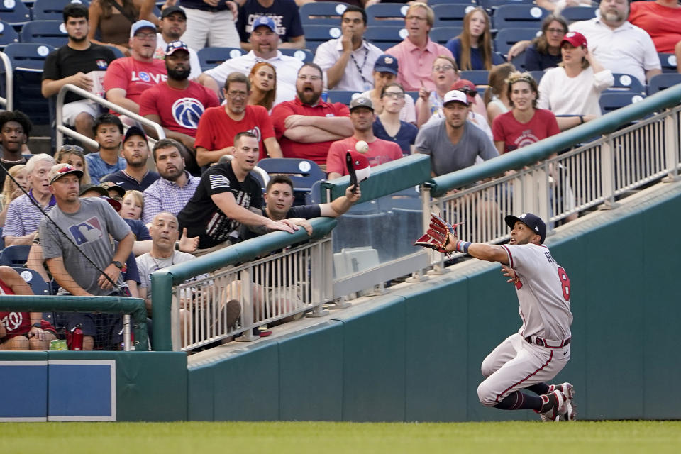 Spectators react as Atlanta Braves left fielder Eddie Rosario prepares to catch a fly ball that was hit by Washington Nationals' Cesar Hernandez in the fourth inning of a baseball game, Thursday, July 14, 2022, in Washington. (AP Photo/Patrick Semansky)