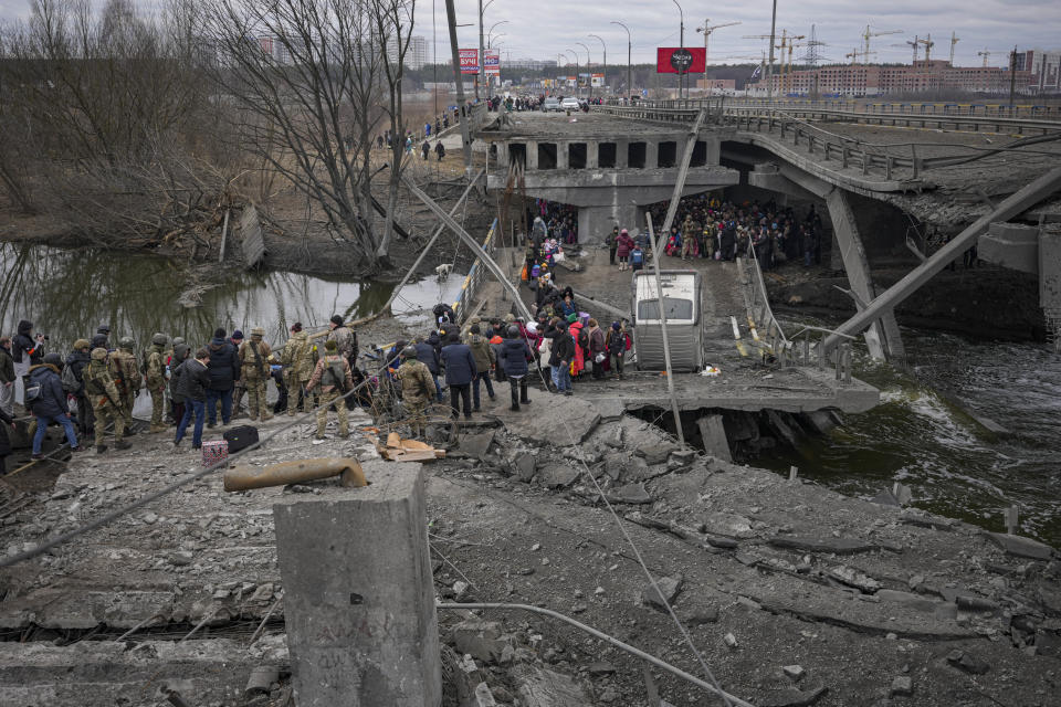 People cross on an improvised path under a bridge that was destroyed by a Russian airstrike, while fleeing the town of Irpin, Ukraine, Saturday, March 5, 2022. What looked like a breakthrough cease-fire to evacuate residents from two cities in Ukraine quickly fell apart Saturday as Ukrainian officials said shelling had halted the work to remove civilians hours after Russia announced the deal. (AP Photo/Vadim Ghirda)