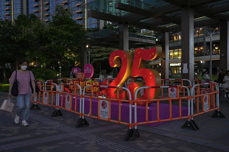 FILE - A woman walks past a sculpture to celebrate the 25th anniversary of Hong Kong handover to China, in Hong Kong, Friday, June 24, 2022. Hong Kong authorities, citing “security reasons,” have barred more than 10 journalists from covering events and ceremonies this week marking the 25th anniversary of Hong Kong’s return to China, according to the Hong Kong Journalists Association, Tuesday, June 28, 2022. (AP Photo/Kin Cheung, File)