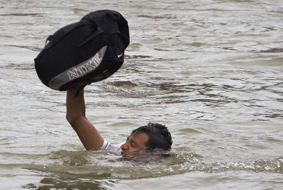 A Central American migrant wades across the Suchiate River, on the the border between Guatemala and Mexico, in Ciudad Hidalgo, Mexico, Saturday, Oct. 20, 2018. After Mexican authorities slowed access through the border bridge to a crawl, hundreds of migrants began boarding rafts or wading across the river and crossing into Mexico illegally.(AP Photo/Moises Castillo)