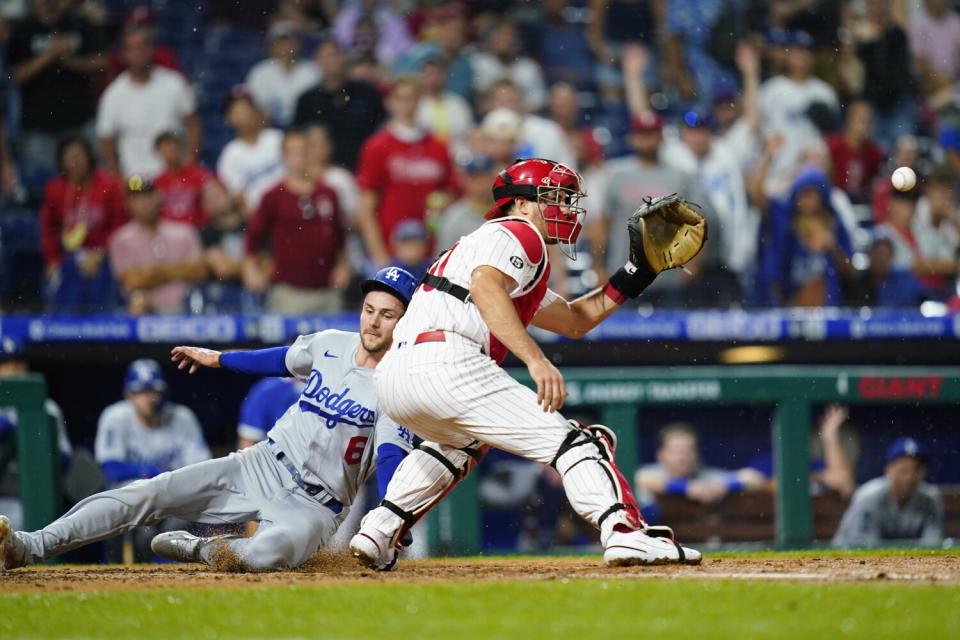 Dodgers' Trea Turner, left, scores past Philadelphia Phillies catcher J.T. Realmuto during a game on Aug. 10, 2021.