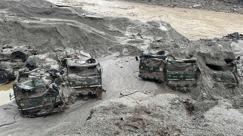 Trucks buried in mud are seen in an area affected by flood in Sikkim