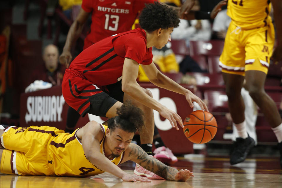 Rutgers guard Derek Simpson, top, gathers control of the ball next to Minnesota guard Braeden Carrington (4) during the first half of an NCAA college basketball game Thursday, March 2, 2023, in Minneapolis. (AP Photo/Bruce Kluckhohn)