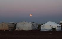 The moon is seen over tents in Azaz