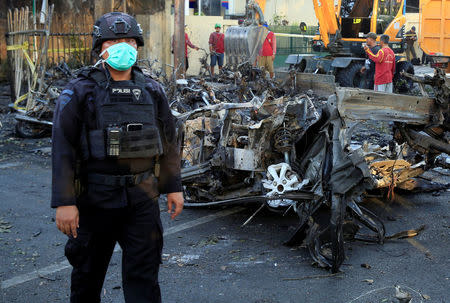 An Indonesian Special Forces Police counter-terrorism member stands near the car wreck that crashed into the church at the Pentecost Church Central Surabaya (GPPS), in Surabaya, Indonesia May 13, 2018. REUTERS/Beawiharta