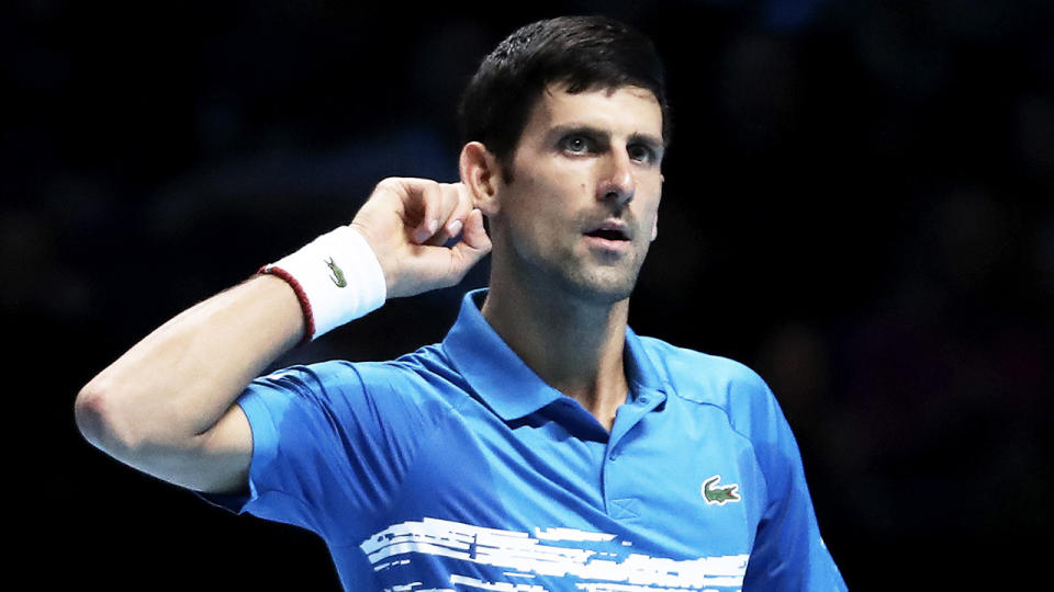 Novak Djokovic gesturing that he can't hear the crowd.