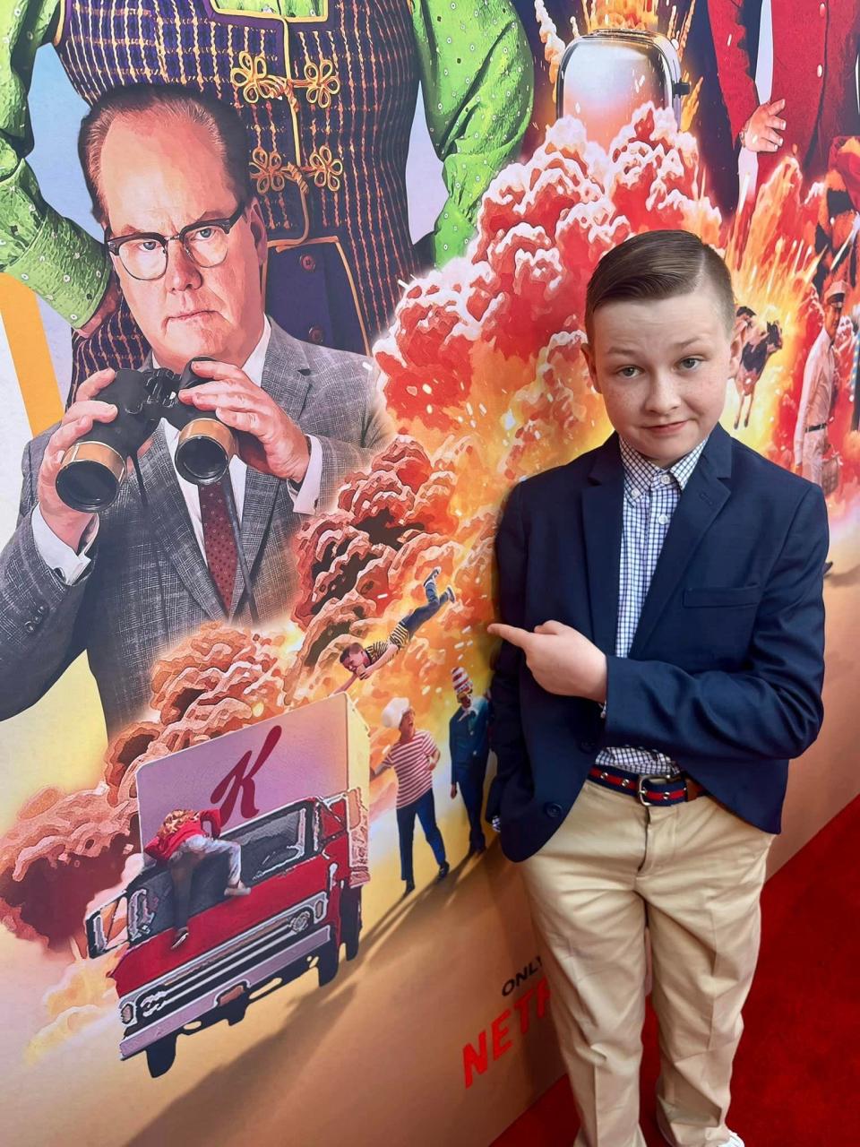 In Hollywood, actor Bailey Sheetz of Chester, Virginia at the premiere of Jerry Seinfeld's movie "Unfrosted" points at his character Butchie flying through the air on the poster.