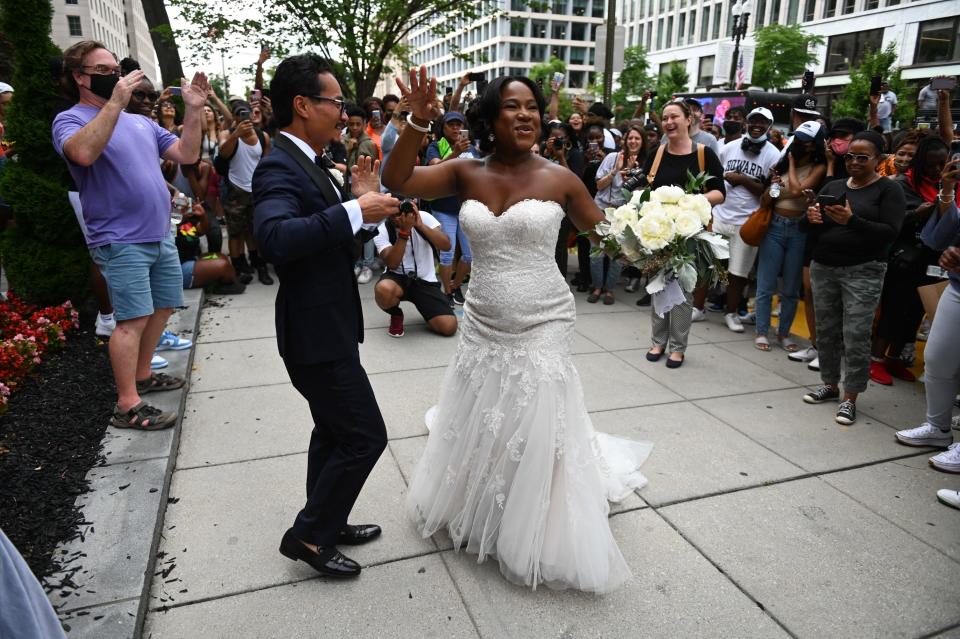 A bride and groom dance as they walk past people celebrating Juneteenth at the Black Lives Matter Plaza in Washington, DC.