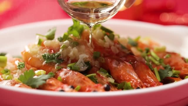 Pouring hot oil over steamed prawns