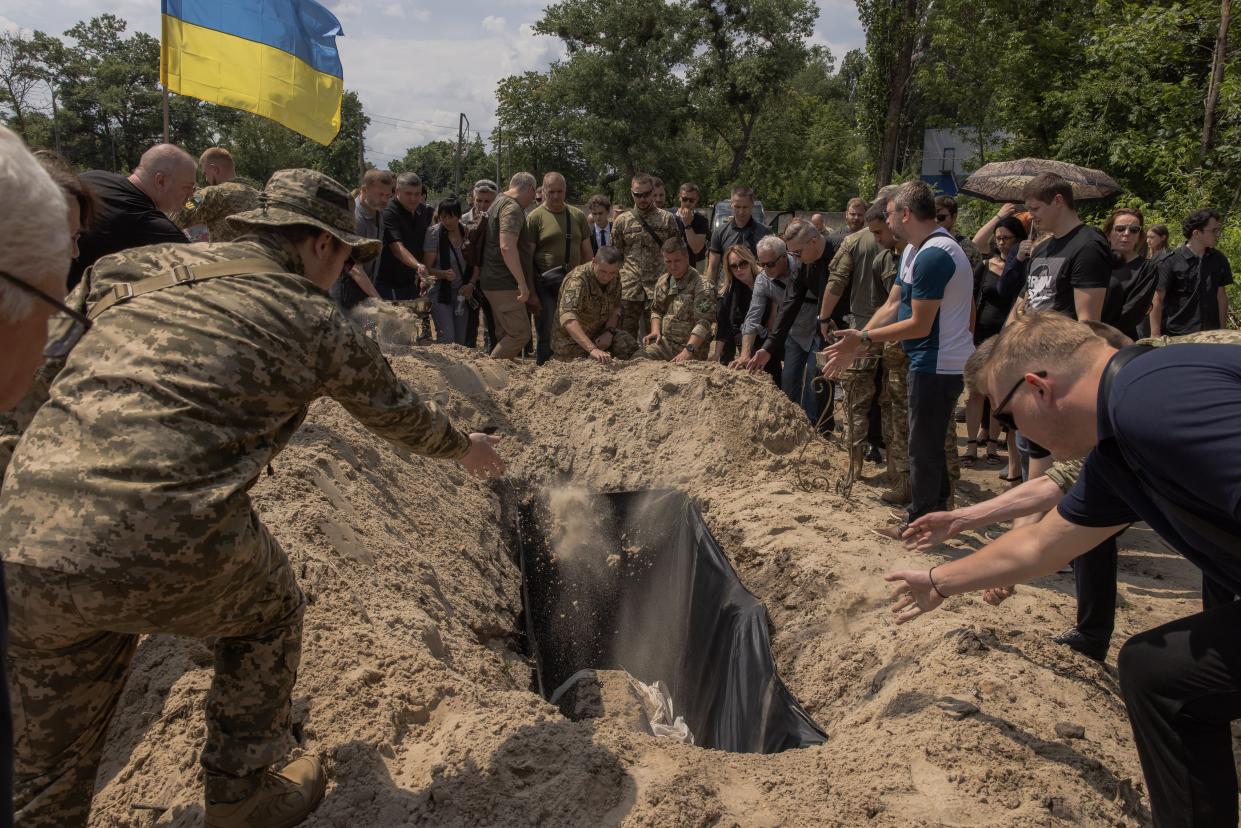 Relatives and friends toss handfuls of soil on top of the coffin of Anton Klitnyi (Getty Images)