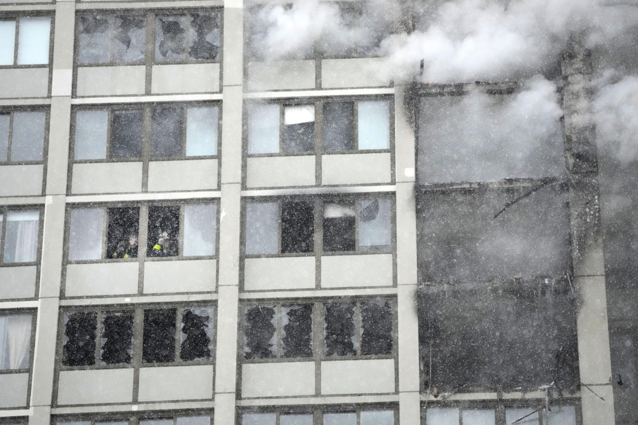 Chicago firefighters look out windows a few floors below where flames leap skyward at the Harper Square cooperative residential building in the Kenwood neighborhood of Chicago, Wednesday, Jan. 25, 2023. (AP Photo/Charles Rex Arbogast)