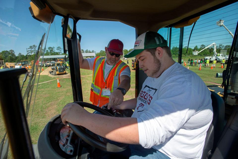 FDOT equipment operator Chandler Pendelton teaches Tate High School student Trey Richardson how to operate a front-end loader during a Construction Career Day event in Milton on Wednesday.