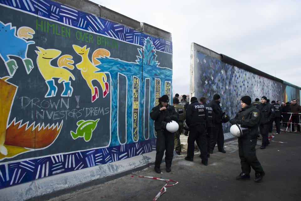 German police officers protect a part of the former Berlin Wall in Berlin, Germany, Friday, March 1, 2013. Construction crews stopped work Friday on removing a small section from one of the few remaining stretches of the Berlin Wall to make way for a condo project after hundreds of protesters blocked their path. (AP Photo/Markus Schreiber)