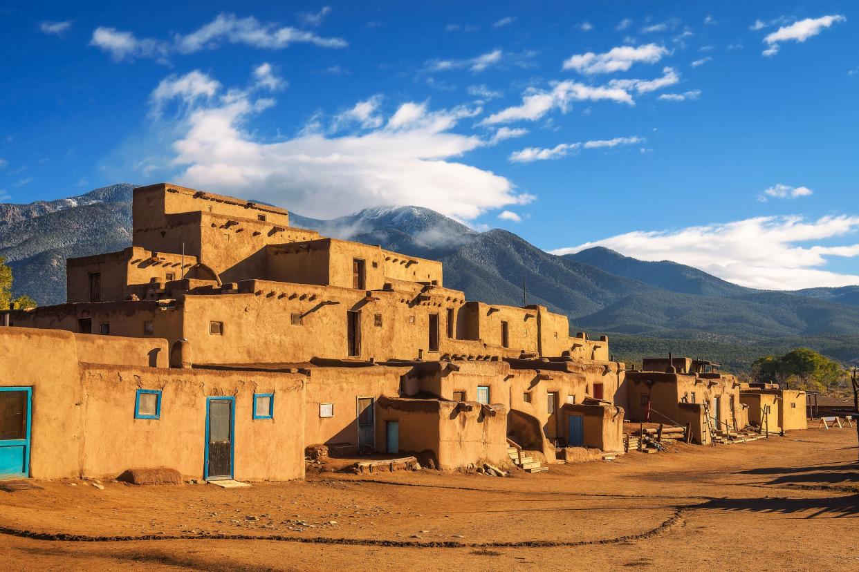 Old clay buildings with mountains and blue sky in background