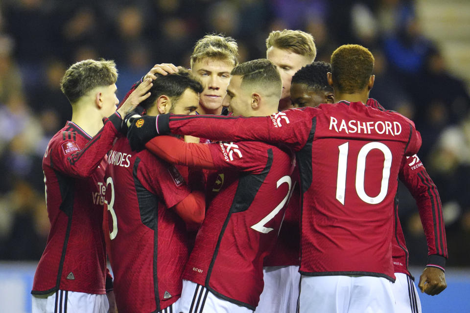 Manchester United players celebrate after Manchester United's Bruno Fernandes scored his side's second goal during the English FA Cup third round soccer match between Wigan Athletic and Manchester United at the DW Stadium, Wigan, England, Monday, Jan. 8, 2024. (AP Photo/Jon Super)