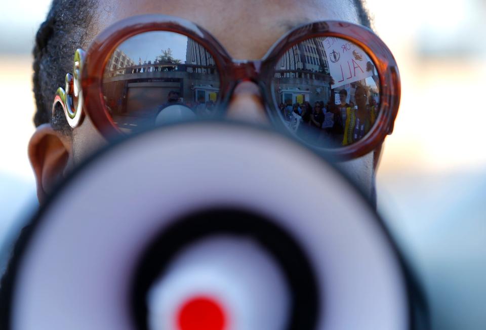 Protesters reflect in Pamela Moses' sunglasses while she leads chants with a bull horn in 2017.